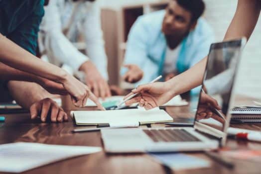 A photo of a desk and people gathered around it. In September Canada made more positive strides towards returning to pre-pandemic business activity