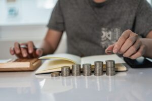 Young man and pile of coins to plan increasing savings strategy with pile of coins for future planning fund.