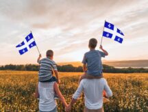 A family waving the Quebec provincial flag while standing in a field