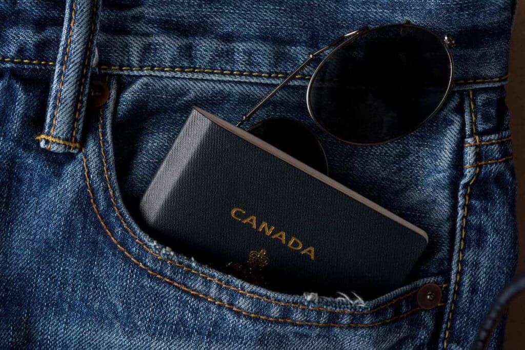 A picture of a passport in a person's jean pocket with a pair of sunglasses.