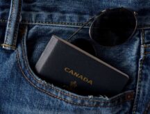 A picture of a passport in a person's jean pocket with a pair of sunglasses.