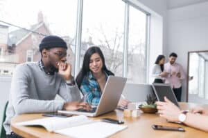 Students stare at a laptop on a table in front of them