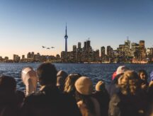 A group of people on Toronto island, looking at the main city from across the water