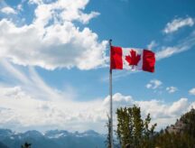 A Canadian flag waving in the wind on a bright day.