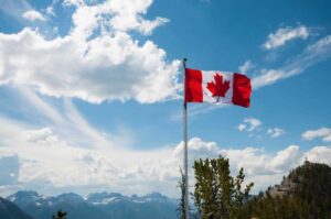 A Canadian flag waving in the wind on a bright day.