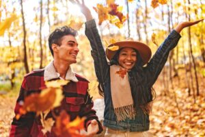 A man and a woman surrounded by fall foliage