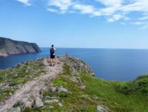 A man takes a photo of the ocean while trekking through Newfoundland and Labrador, Canada