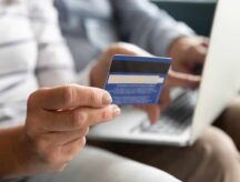 A couple looks to their laptop, credit card in hand, anticipating the online payment of their IRCC fees.