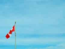 The Canadian flag against a bright blue sky