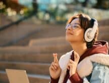 A young woman crosses her fingers in anticipation and hope that she may receive some good news.