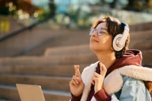 A young woman crosses her fingers in anticipation and hope that she may receive some good news.