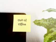 An Out-Of-Office post-it stuck on a laptop