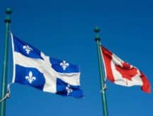 The Quebec and Canadian flags blowing in the wind on a summer day