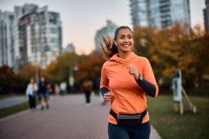 A woman wearing headphones smiles while jogging