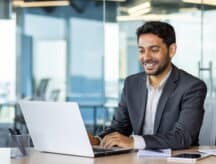 A man smiles while looking at his laptop