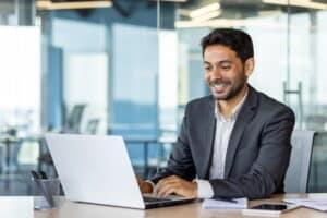 A man smiles while looking at his laptop