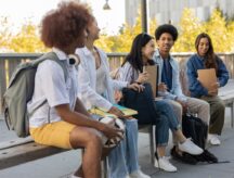 A group of diverse international students sit on a bench