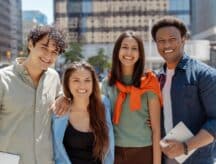 A group of young people looking at a camera in the middle of a city on a bright day