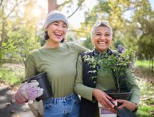 Two women planting plants in a community garden as part of a newcomer community event