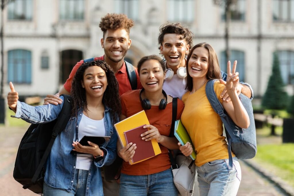 A group of students pose on their college campus.