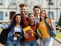 A group of students pose on their college campus.