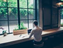 A person sitting in a library at a window, working on their laptop