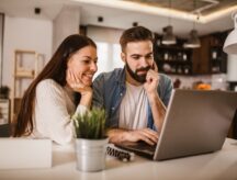 A couple sitting at a laptop considering their sponsorship options