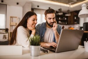 A couple sitting at a laptop considering their sponsorship options