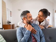 A couple being happy on the couch after applying for an Open Work Permit