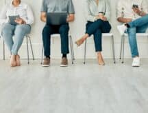 Four people sit on chairs while waiting to be interviewed