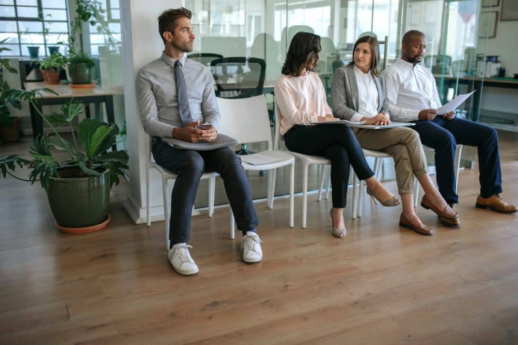 People in corporate attire siting, waiting for a job interview.