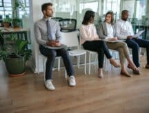 People in corporate attire siting, waiting for a job interview.