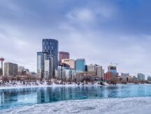 Ice flows down the partially frozen Bow River with the Calgary skyline in the background.