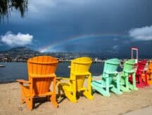 A row of colourful chairs overlooking a rainbow in Kelowna on a rainy day