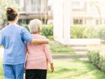 A elderly woman and her home care giver consider the latter's immigration options to Canada while looking at a residential park outside of the nursing home.