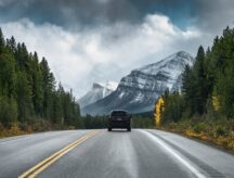 A car driving on an empty road toward a scenic mountain view