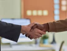 two people shaking hands, one dressed in professional attire