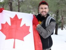 A man holds a giant flag of Canada