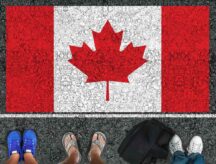 Different feet stand on asphalt with a Canadian flag drawn on the road.