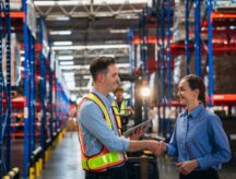 Two workers in a warehouse shake hands