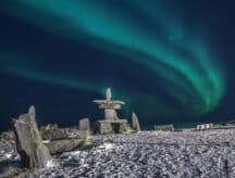 A traditional indigenous stone sculpture set against the backdrop of the northern lights.